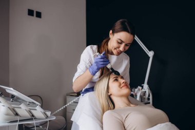 Ultrasonik temizleyicisi olan bir güzellik uzmanı kadın derisi ile çalışır. Deriyi siyah noktalardan ve diğer safsızlıklardan arındırıyor. Ultrasonik yüz soyuluyor.