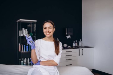 Dermapen cihazı olan bir kozmetikçinin portresi..