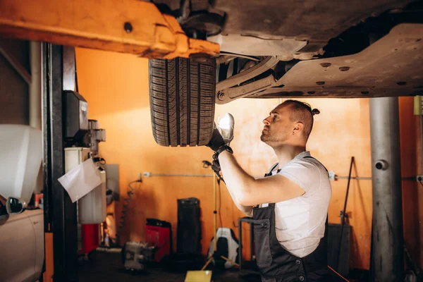 修理ガレージで懐中電灯を使用して車のタイヤを調べる機械 — ストック写真