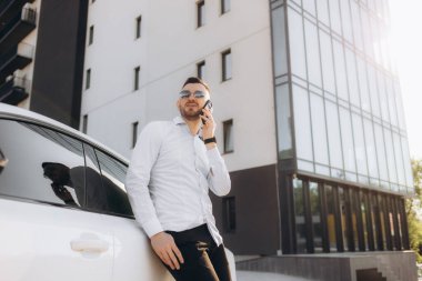 Yakışıklı cep telefonu araması gülümseme açık şehir sokağı genç çekici iş adamı günlük mavi gömlek konuşması orta yaşlı iş adamı akıllı telefon konuşması modern ofis binası.