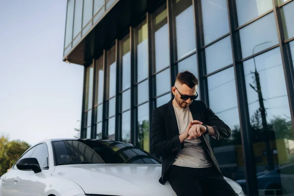 stock image Man waiting minded customer male buyer client in grey suit choose auto look at time smart watch want buy new automobile in car showroom vehicle salon dealership store motor show indoor Sales concept