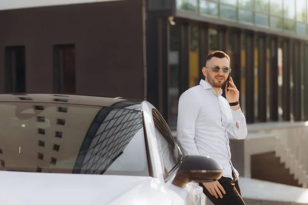 商人站在汽车旁边用智能手机交谈 — 图库照片