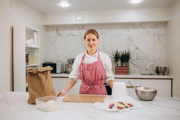 stock image Confectioner in a kitchen. Woman in a uniform. Professional decorates the macaroni