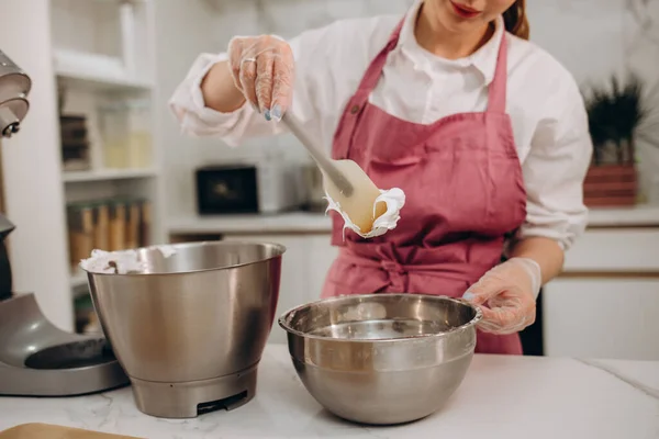 菓子職人の女性の肖像料理を準備エプロンで 弓で卵をむさぼる少女 主婦は泡立て器で台所に立っている ホイップクリームを作る若い女性 おいしい料理のコンセプト — ストック写真