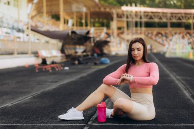 Sporcu kadın koşudan sonra koşu bandında oturur..