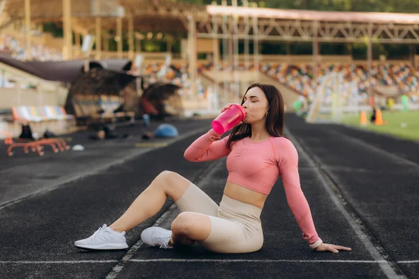 競技場でジョギングした後に水を飲むフィットネス女性 — ストック写真