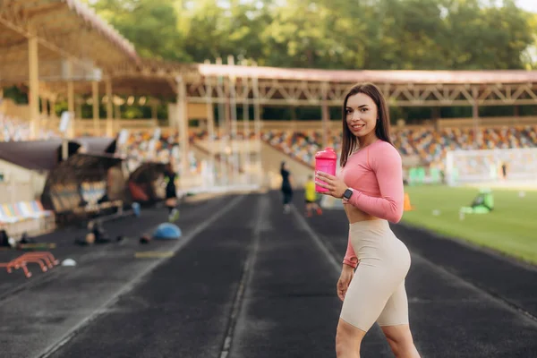 stock image Portrait of happy woman holding water bottle on race tracks