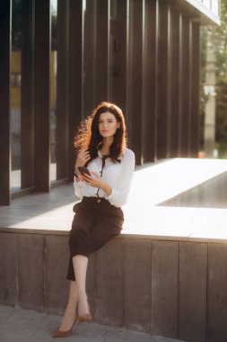 Başarılı bir iş kadını ya da girişimci dışarıda yürürken not alıp cep telefonuyla konuşuyor. Şehir iş kadını çalışıyor