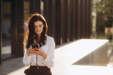 Başarılı bir iş kadını ya da girişimci dışarıda yürürken not alıp cep telefonuyla konuşuyor. Şehir iş kadını çalışıyor