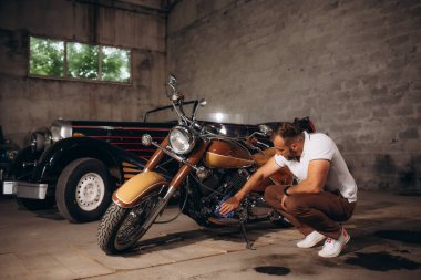 Bir adam retro motorun motorunu siliyor. Araba ve motosiklet koleksiyoncusu..