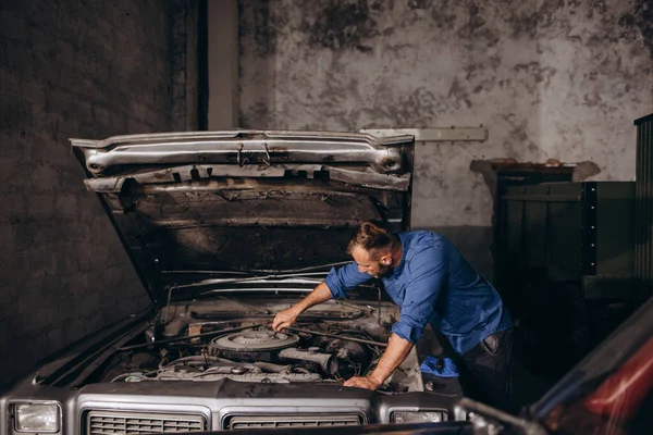 男はレトロな車を収集します 男はレトロな車のエンジンを修理する — ストック写真