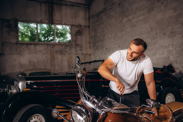 一个中年男人在车库里修理他那辆复古的摩托车 — 图库照片