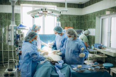 Tıbbi ekip sezaryen yapıyor. Doktor görmek için annesini doğururken bebeği kucağına aldı.