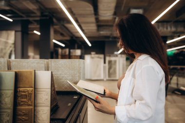 Mutlu esmer kadın iç mimar mağazadan döşeme rengi doku örneklerini seçiyor. Mimarlık ve inşaat endüstrisi için yer ve duvar malzemesi seçen kadın mimarı.