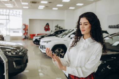 Pano tutan kameraya gülümseyen profesyonel araç Bayi Oto showroom, gururla poz. Mutlu pazarlamacı otomobil Bayilik, kopya alanı çalışma. Profesyonellik, yönetim kavramı