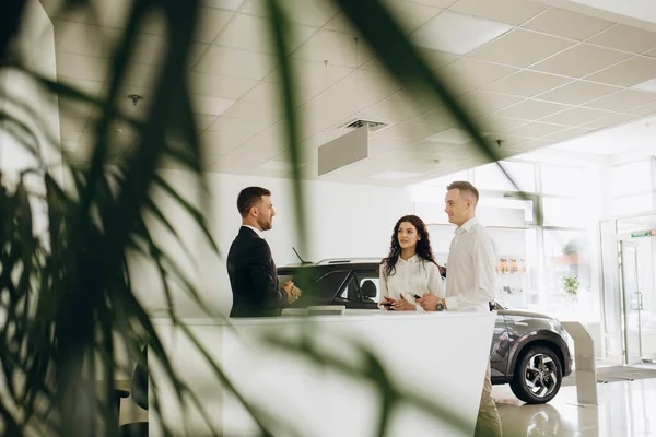 stock image Middle age couple choosing and buying car at car showroom. Car salesman gives them car keys