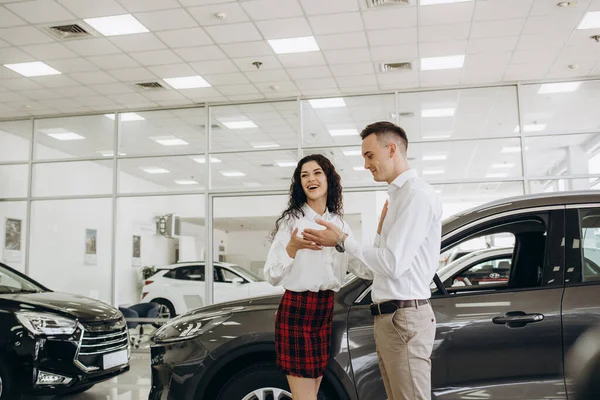 stock image Beautiful young smiling couple holding a key of their new car.