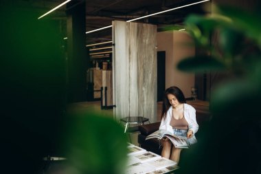 Bir kadın DIY mağazasındaki malzeme kataloğuna bakar..