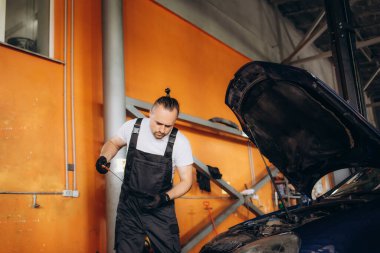 Tamirci araba atölyesinde yağ seviyesini kontrol ediyor..