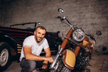 Bir adam eski motosikletini tamir eder..