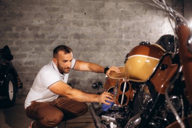 Bir adam eski motosikletini siliyor..