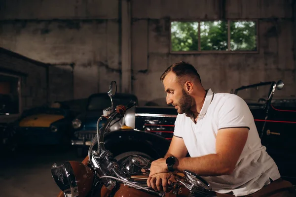 a man sits on a motorcycle in a garage.