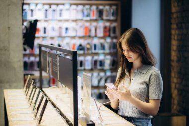 Mağazada akıllı telefon kullanan bir kadının yan görünümü.