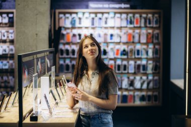 Mağazada akıllı telefon kullanan bir kadının yan görünümü.