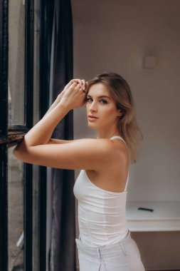 Güzel sarışın pencerenin yanında duruyor..