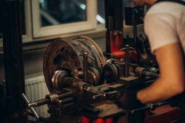 Araba servisinde tekerlek hizalaması için kırmızı üniformalı yakışıklı oto tamircisi. Yüksek kalite fotoğraf