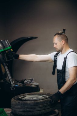 Araba servisinde tekerlek hizalaması için kırmızı üniformalı yakışıklı oto tamircisi. Yüksek kalite fotoğraf