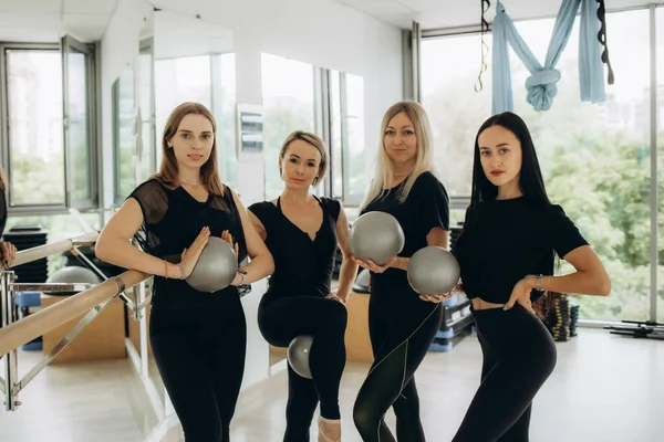 Four women in fitness wear standing together for a selfie after workout. Women laughing and showing muscles while standing for a selfie at a fitness studio. High quality photo