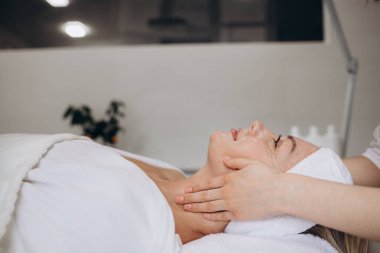 Kadın bir müşterinin yüzünü kozmetoloji prosedürlerinden önce yıkamak ve kurutmak. Profesyonel kozmetolog modern sağlık ve güzellik kliniğinde yüz temizliği yapıyor. Yüksek kalite fotoğraf