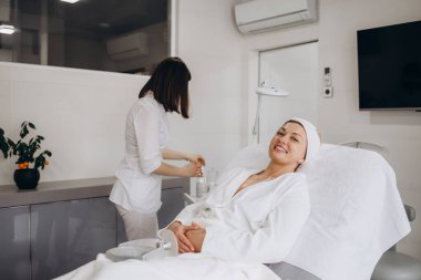 Estetik prosedür. Güzellik Uzmanı Orta Çağ Kadın Yüzüne Çamur Yüzlü Maske Uyduruyor Kozmetik Stüdyosunda Yaşlanma Karşıtı Cilt Tedavisinden Hoşlanan Çekici Kadın, 