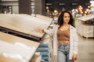 İnşaat mağazasının zemin kaplamalı deposunda, yansıtıcı müşteri bu mağazadan kaplama döşeme satın almayı düşünüyor. Yüksek kalite fotoğraf