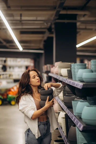a woman chooses a pot for flowers in a store.