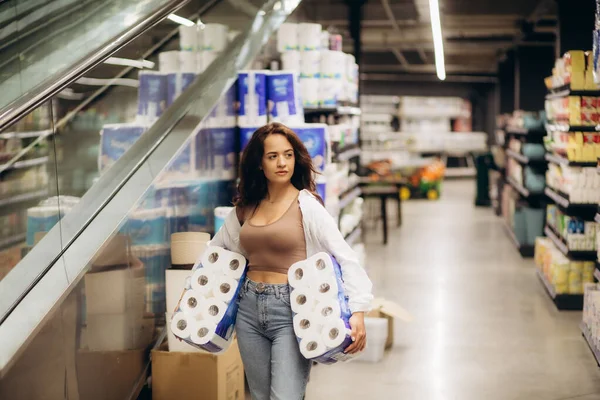 Young woman looking to buy pack of toilet paper in supermarket. High quality photo