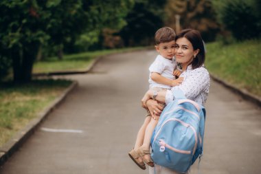Çocuk okula geri dönüyor. Anne ve çocuk tatilden sonraki ilk okul günü için hazırlanıyorlar. Küçük çocuk ve annesi anaokuluna ya da anaokuluna gidiyor. Öğrenci sırt çantasında kitap, elma ve öğle yemeği paketliyor. Yüksek kalite fotoğraf