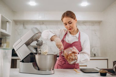 Modern mutfak makinesine ve mutfaktaki masa üzerindeki tahta kesme tahtasına odaklan. Önlüklü genç bir kadın. Yüksek kalite fotoğraf