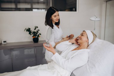 Kozmetik uzmanı yüz tedavisi yapıyor ve yüz maskesi takıyor. Yüksek kalite fotoğraf