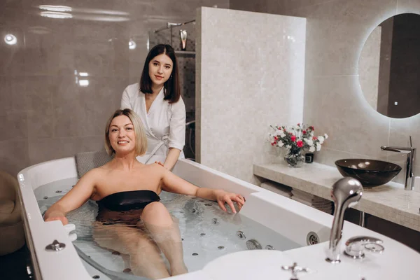 Dönen havuz banyosunda hidromasaj yaptıran bir kadının dikiz görüntüsü. Spa merkezindeki profesyonel güzellik uzmanından hidromasaj yaptıran rahat bir kadın. Yüksek kalite fotoğraf