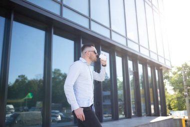 Şehirde cep telefonu kullanan ve kahve içen kendine güvenen genç bir işadamı. Yüksek kalite fotoğraf
