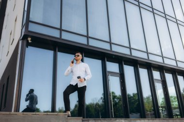 Yakışıklı hippi, sakallı, modern iş adamı kasabada yürüyor ve cep telefonundan arıyor. Yüksek kalite fotoğraf