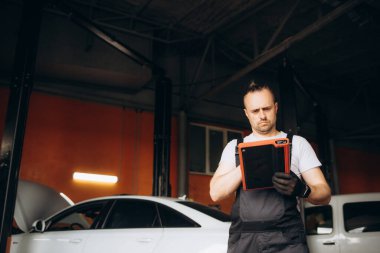 Otomobil tamirhanesinde dijital tablet kullanan mutlu bir tamirci. Yüksek kalite fotoğraf