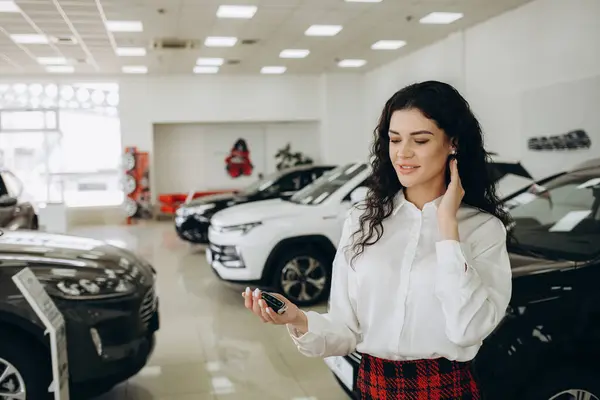 beautiful young car sales consultant using smart phone at showroom. High quality photo