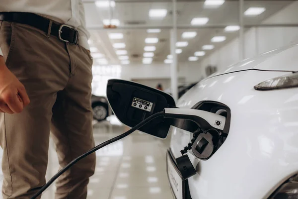 Human hand is holding Electric Car Charging connect to Electric car. High quality photo