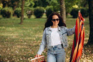 Bir kadın hamağı ağaca açar ve bağlar.