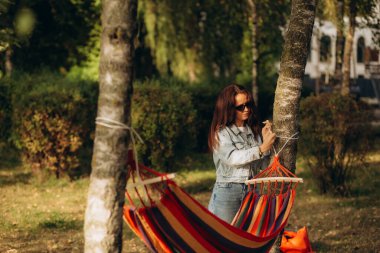 Bir kadın hamağı ağaca açar ve bağlar.