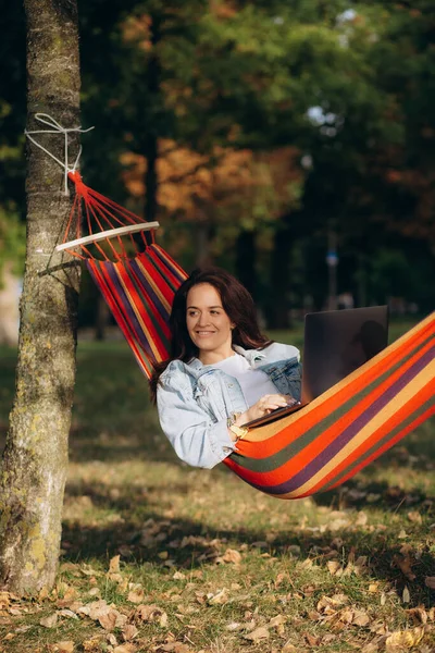 woman lies in a hammock with a laptop on nature headphones rest technology. High quality photo