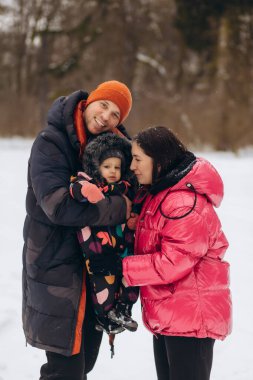 Mutlu genç aile kışın dışarıda vakit geçirir (babaya odaklan). Yüksek kalite fotoğraf